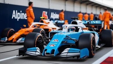 La monoplace Alpine F1 bleue aux accents blanc et orange dans la voie des stands, près du logo Alpine.