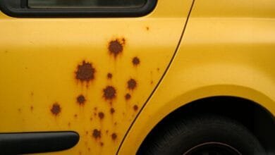Côté d'une voiture jaune avec de nombreuses taches de rouille.