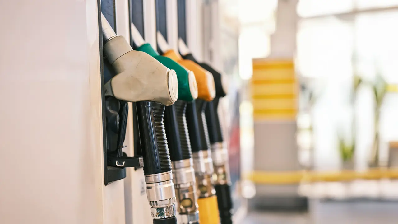 Station-service avec pistolets à carburant multicolores (vert, orange) accrochés aux pompes à essence.RéessayerClaude peut faire des erreurs. Assurez-vous de vérifier ses réponses.
