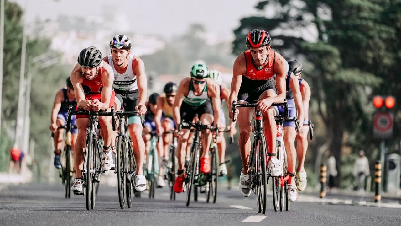 Cyclistes en position aérodynamique lors d'une course de triathlon, pédalant en groupe sur route urbaine.RéessayerClaude peut faire des erreurs. Assurez-vous de vérifier ses réponses.